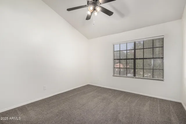 an empty room with a window and ceiling fan