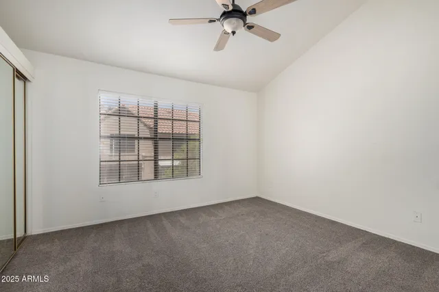 an empty room with chandelier fan and windows