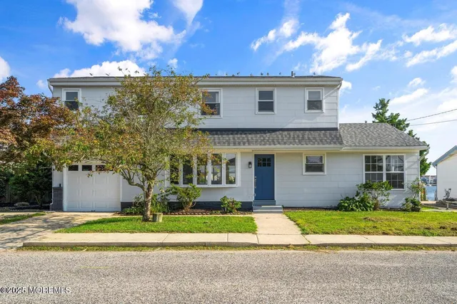 a front view of a house with a yard and potted plants