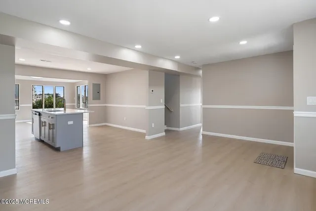 a view of an empty room with wooden floor and a kitchen
