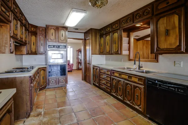 a kitchen with granite countertop a sink a counter top space and cabinets