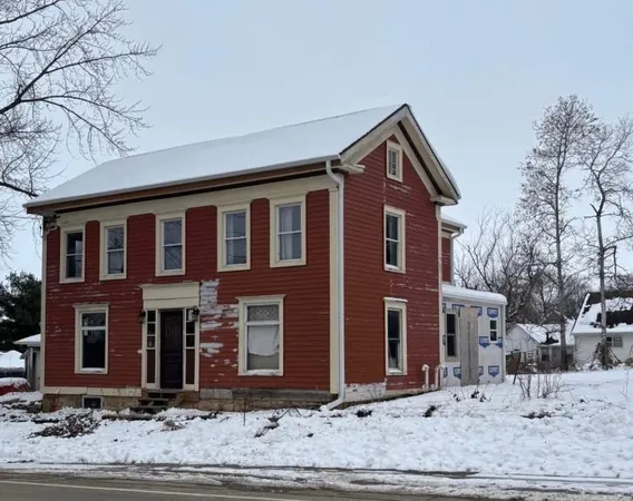 a front view of a house with a yard and car parked