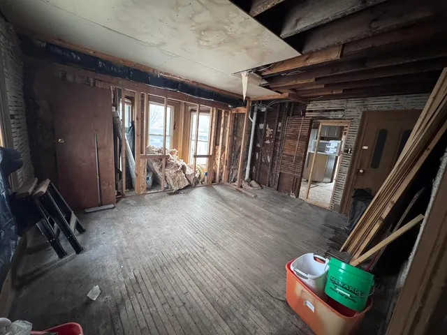 a view of an empty room with wooden floor and windows