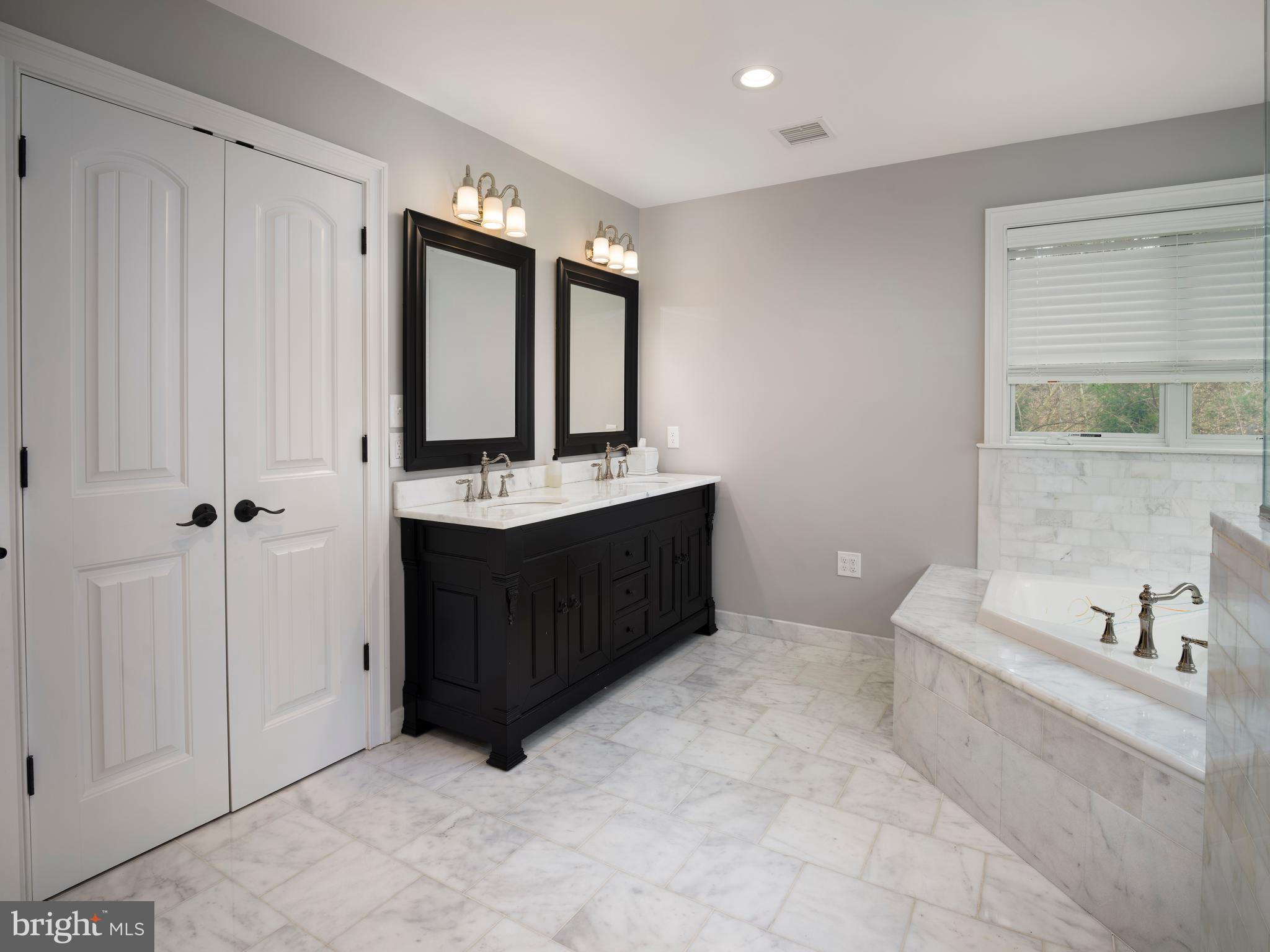 1685 Valley Road Newtown Square, PA 19073 - Photo 37 of 53 a bathroom with a double vanity sink a mirror and a bathtub