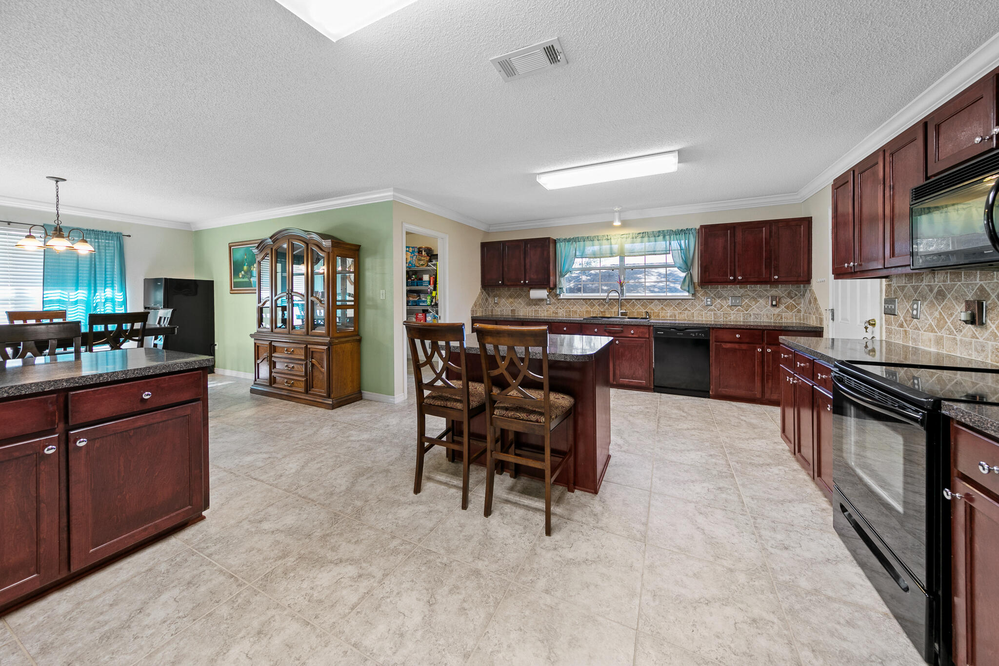 6735 Britt Street Navarre, FL 32566 - Photo 17 of 42 a kitchen with stainless steel appliances granite countertop a stove top oven a sink dishwasher a dining table and chairs