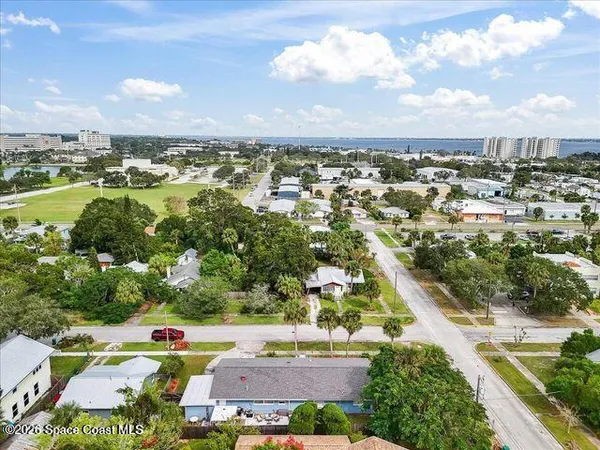 an aerial view of a city with lots of residential buildings ocean and mountain view in back