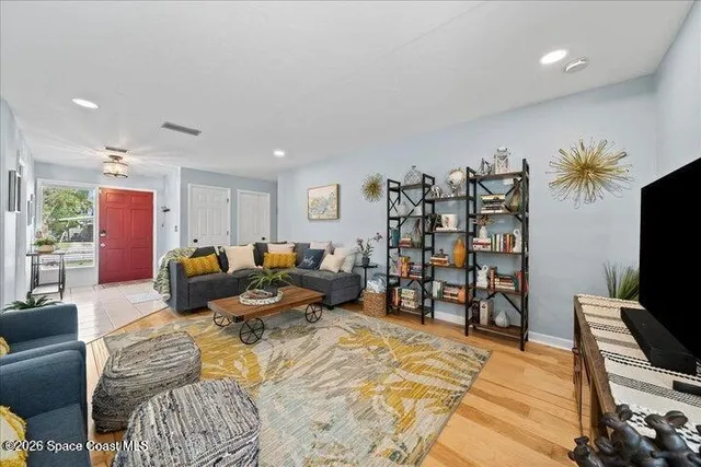 a living room with furniture a flat screen tv and a refrigerator