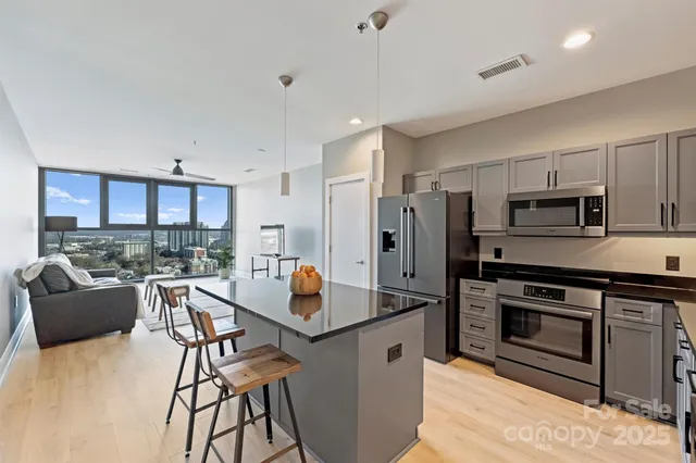 a kitchen with stainless steel appliances kitchen island granite countertop a dining table chairs refrigerator and sink