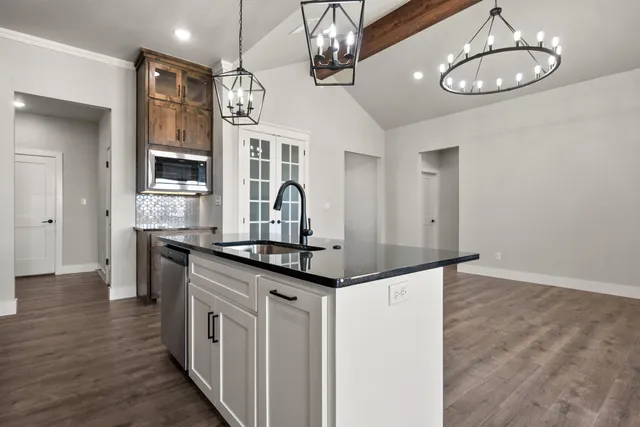 a kitchen with stainless steel appliances granite countertop a sink cabinets and wooden floor