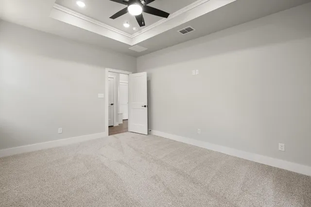 an empty room with chandelier fan and windows