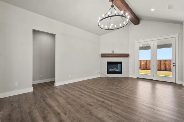 an empty room with wooden floor a fireplace and window