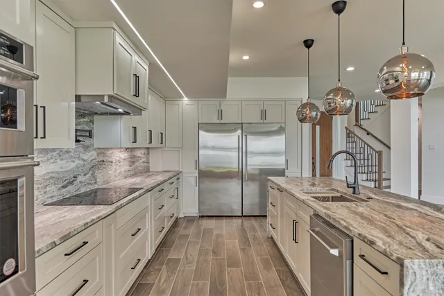 a kitchen with stainless steel appliances granite countertop a sink a stove and a refrigerator