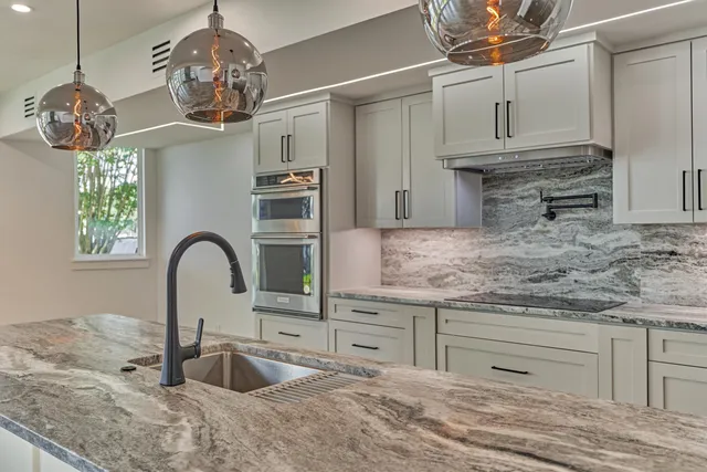 a kitchen with stainless steel appliances granite countertop a sink a stove and a wooden floors