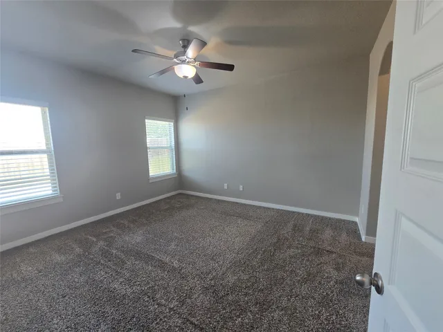 an empty room that has a chandelier fan and a window