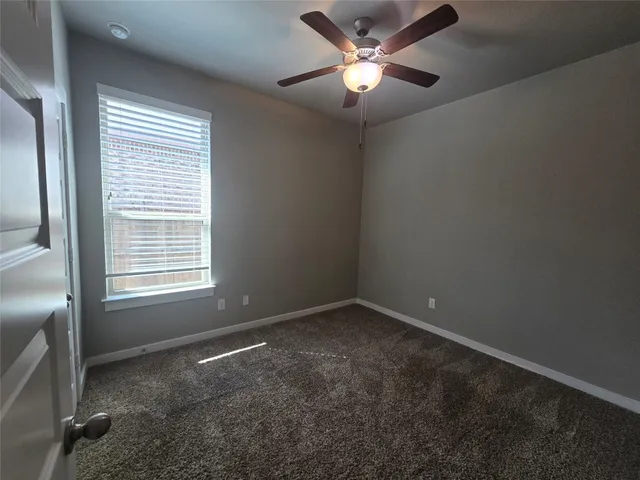 an empty room with a window and a fan