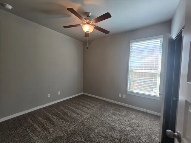 an empty room with a chandelier fan and windows
