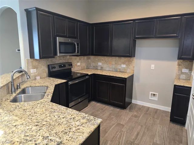 a kitchen with granite countertop wooden cabinets and stainless steel appliances
