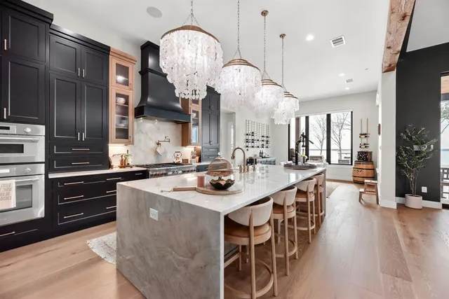 a kitchen with stainless steel appliances a center island wooden floor stove a sink and a refrigerator