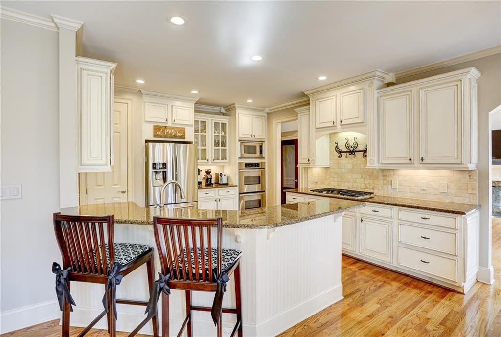 11015 Callington Court Suwanee, GA 30024 - Photo 24 of 87 a kitchen with stainless steel appliances granite countertop a stove top oven a sink a dining table and chairs