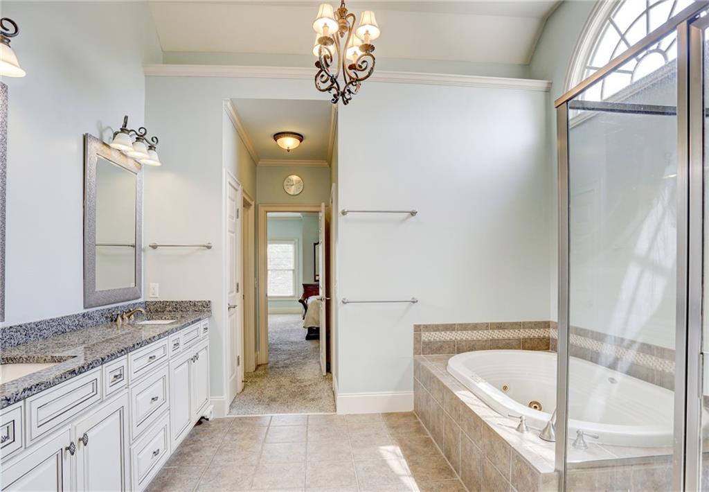 11015 Callington Court Suwanee, GA 30024 - Photo 48 of 87 a spacious bathroom with a granite countertop sink a mirror and a bathtub