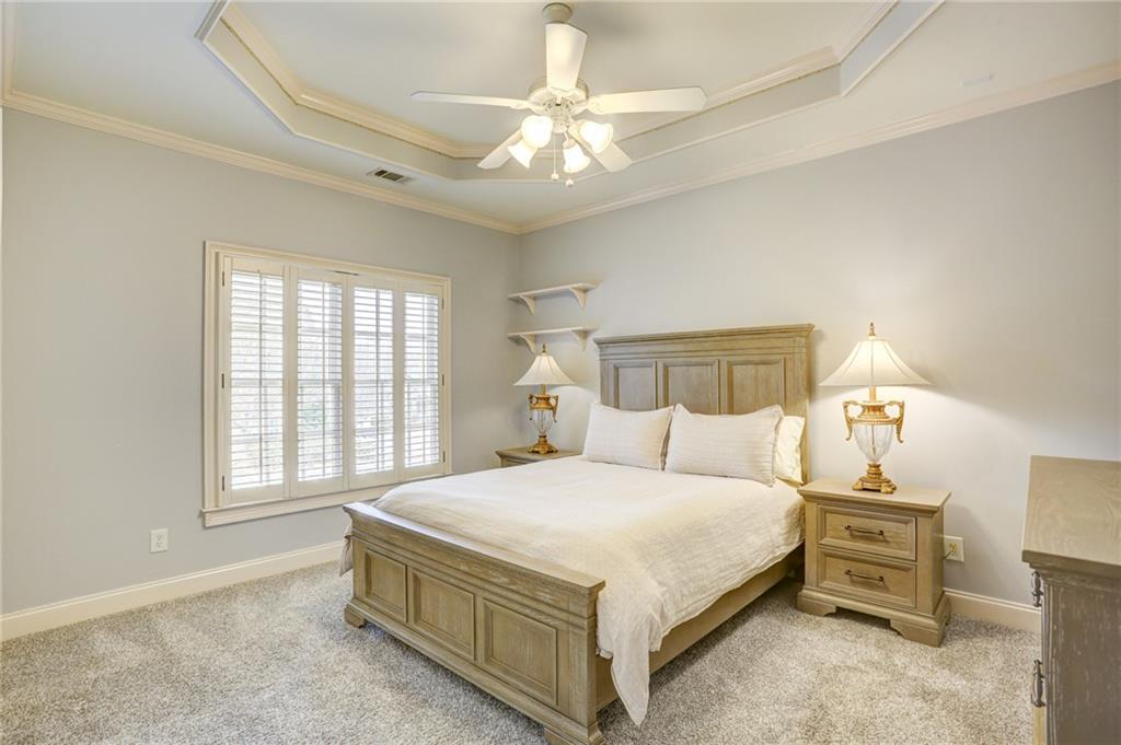 11015 Callington Court Suwanee, GA 30024 - Photo 54 of 87 a bedroom with a large bed and a chandelier fan