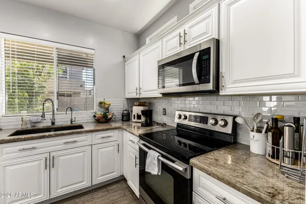 a kitchen with stainless steel appliances granite countertop white cabinets and a stove top oven