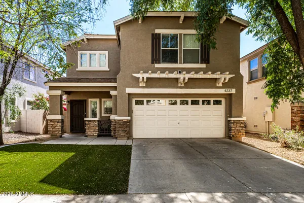 a view of a white house with a large window and a yard with plants