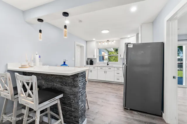 a kitchen with granite countertop a table chairs refrigerator and microwave