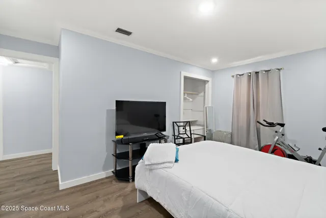 a bedroom with a bed and a flat tv screen on wall