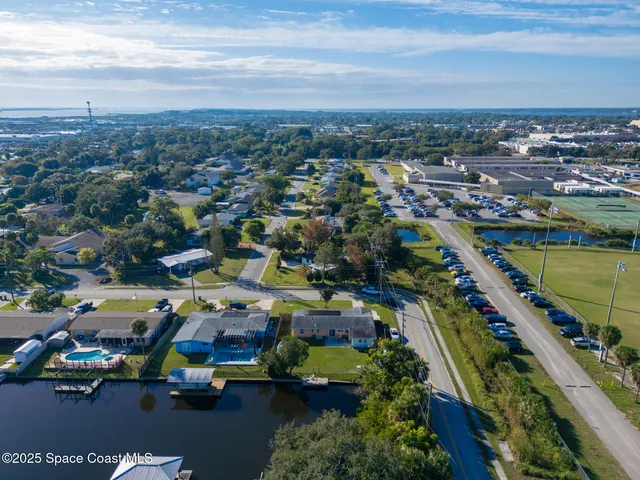 an aerial view of a resort with swimming pool tennis courts and ocean view