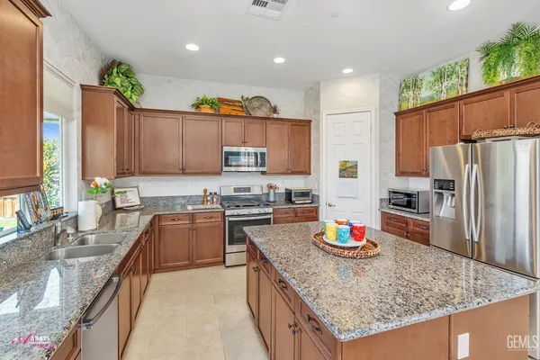 a kitchen with kitchen island granite countertop wooden cabinets a refrigerator and a sink