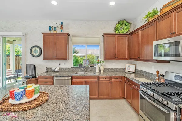 a kitchen with granite countertop a sink and a white wooden cabinets