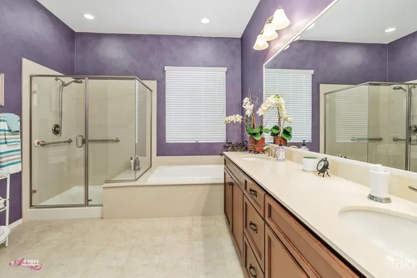 a spacious bathroom with a double vanity sink a large mirror and shower