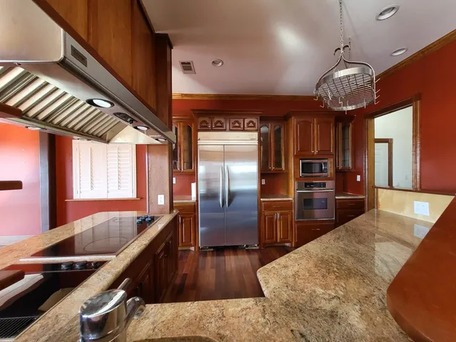 a kitchen with stainless steel appliances granite countertop a sink a stove and a refrigerator