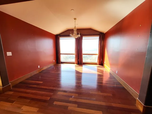 a view of an empty room with window and wooden floor