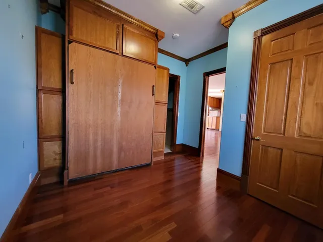 an empty room with wooden floor and entrance