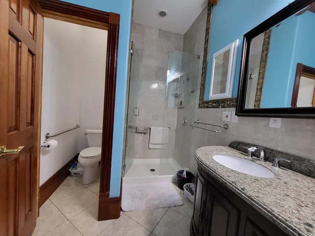 a bathroom with a granite countertop sink a toilet and a mirror