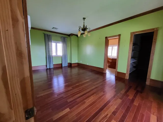 a view of an empty room with window and wooden floor