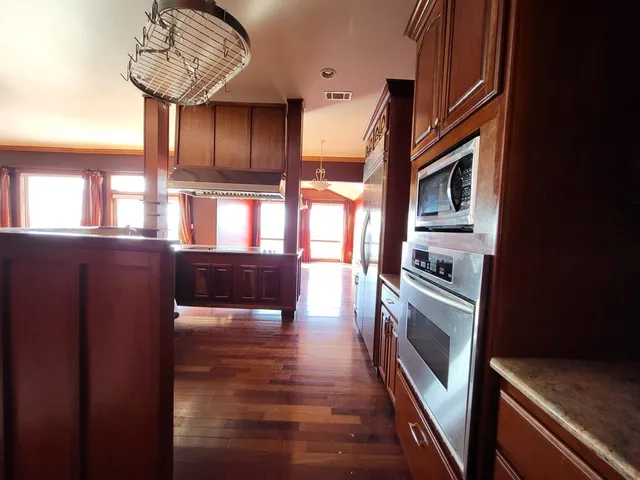 a kitchen with stainless steel appliances granite countertop a refrigerator a stove and a sink with wooden floor