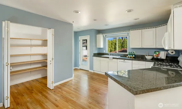 a kitchen with granite countertop a stove a sink and a refrigerator