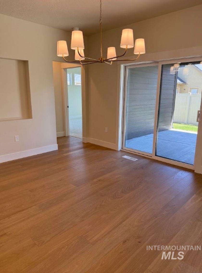 683 West Wrangler Street Meridian, ID 83646 - Photo 9 of 23 Spacious room featuring wide plank wood-finish flooring, a contemporary chandelier with multiple shades, and a large sliding glass door
