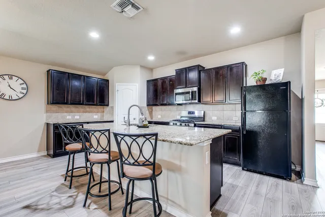 a kitchen with stainless steel appliances granite countertop a table chairs sink refrigerator and microwave