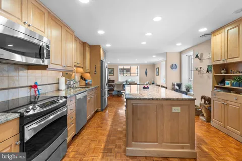 a kitchen with kitchen island granite countertop wooden cabinets and stainless steel appliances