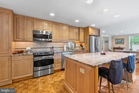a kitchen with granite countertop kitchen island stainless steel appliances a sink stove and cabinets
