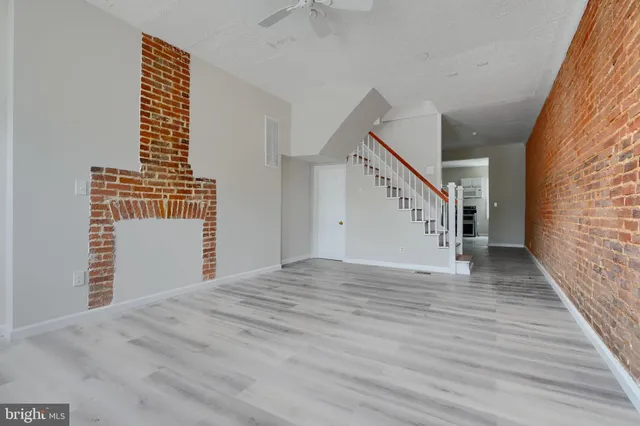 a view of an empty room with wooden floor and a ceiling fan