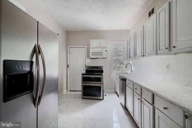a kitchen with stainless steel appliances a refrigerator and a stove top oven