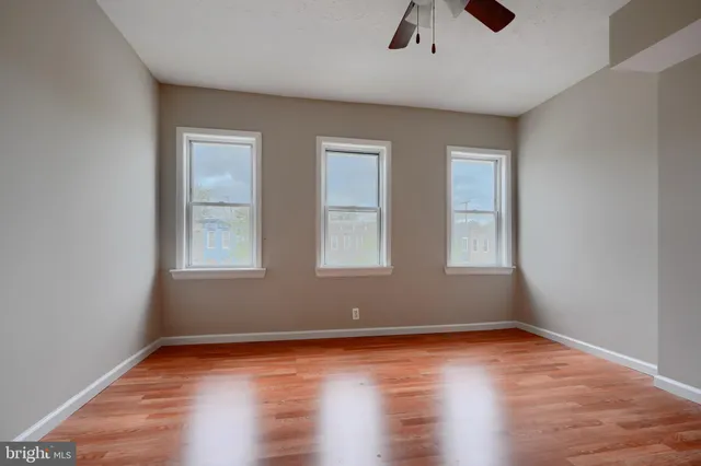 an empty room with ceiling fan and window