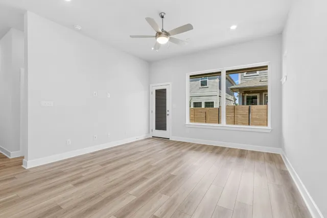 a view of an empty room with wooden floor and a window