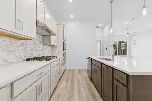a kitchen with stainless steel appliances granite countertop a sink a stove and a wooden floors