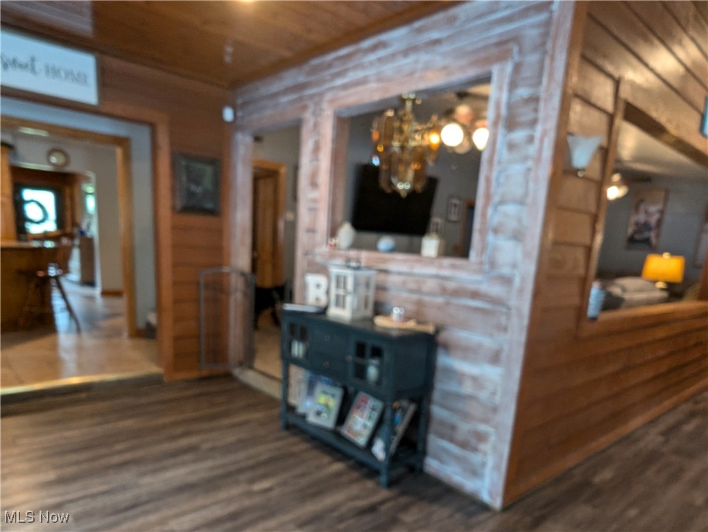 46136 Carlisle Road Lisbon, OH 44432 - Photo 28 of 48 Hallway featuring wood walls, wood ceiling, hardwood / wood-style flooring, and a notable chandelier